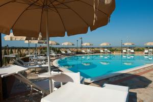 a large swimming pool with chairs and an umbrella at Antico Borgo Casalappi in Campiglia Marittima