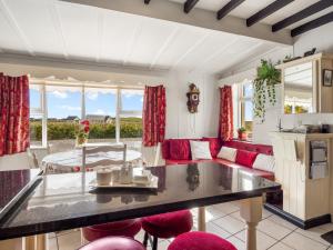 a kitchen and living room with red chairs and a table at Conamara House in Ballyconneely