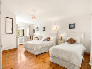 two beds in a bedroom with white walls and wooden floors at Conamara House in Ballyconneely