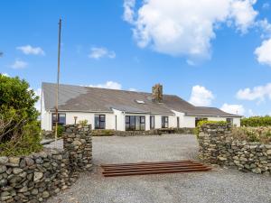 a white house with a stone wall at Conamara House in Ballyconneely