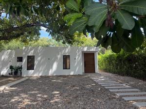 a white building with a door and some trees at Finca Exclusiva en Carmen de Apicalá in Carmen de Apicalá