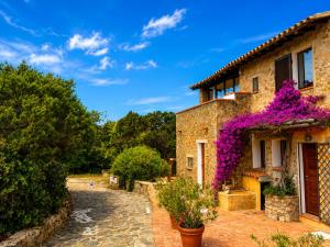 a house with purple flowers on the side of it at Panoramic Sea View Apt 4 Close to the Beach With Pool in Baja Sardinia