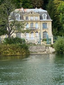 a large house sitting on the side of a river at Péniche - Eden in Samois-sur-Seine