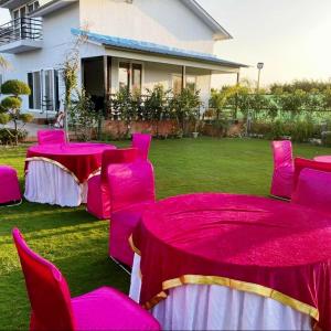 a group of pink tables and chairs in a yard at GoBravo 48 - 2BHK Farm with Pool and Garden Sector 150 Noida in Greater Noida