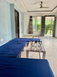 a bedroom with two beds and a table and a fan at GoBravo 48 - 2BHK Farm with Pool and Garden Sector 150 Noida in Greater Noida