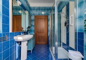 a blue tiled bathroom with a sink and a shower at Hostly The Citrus Garden in Cascina +39 photos