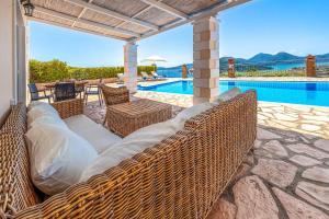 a patio with wicker furniture and a swimming pool at Villa Morfeas in Nydri