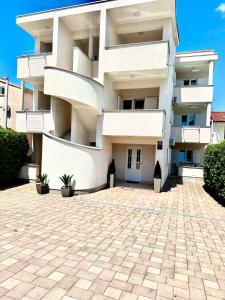 un condominio bianco con un vialetto di accesso in mattoni di Apartmani Samec a Novalja (Novaglia)