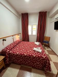 ein Hotelzimmer mit einem roten Bett und roten Vorhängen in der Unterkunft Hotel Emilio in Punta Umbría
