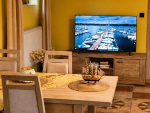 a living room with a table and a tv with boats on it at Apartament Biała Flaga Podwórko, Grill, Rowery in Charzykowy