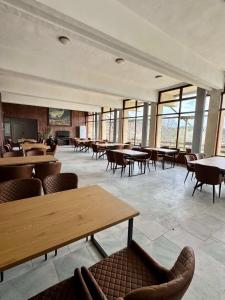 a large room with tables and chairs and windows at Хижа Оборище in Oborishte