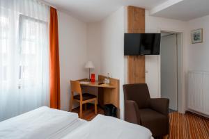 a hotel room with a bed and a chair and a desk at Gasthaus zur Krone in Weingarten (Karlsruhe)