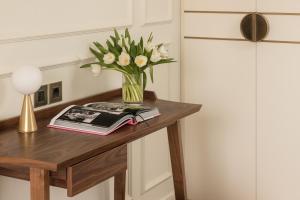 a vase of flowers on a table with a book at Villa Costanza Boutique Hotel in Forte dei Marmi