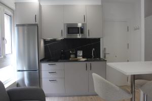 a kitchen with white cabinets and a stainless steel refrigerator at Apartamentos Dulce Estrela in Tui