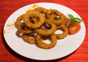a plate of onion rings and a tomato on a table at casa de esteban in Puerto Iguazú +1 photo