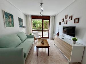 a living room with a green couch and a tv at Apartamento Playa Azul - 5924 in Arnuero