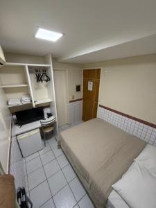 a small bedroom with a bed and a desk at Hotel Ideal in Teresina