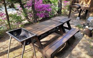 a wooden picnic table and a grill with purple flowers at Goesan Jakeun Saejae Pension in Koesan +4 photos