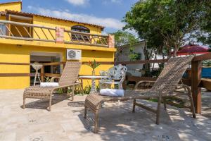two chairs and a table in front of a yellow building at Portal de Búzios in Armacao dos Buzios