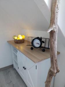 a counter with a clock and a bowl of fruit at Beau duplex coeur historique et plages in Dives-sur-Mer