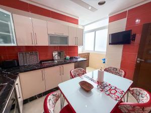 a small kitchen with a white table and chairs at Abraj Dubai - Premium 3BR Stay in Heart of Larache in Larache