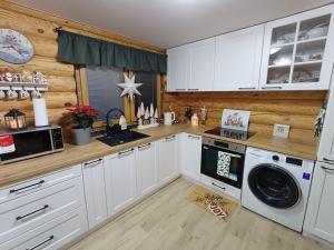 a kitchen with white cabinets and a washer and dryer at Zrub Zuzana in Koš