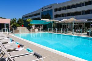 a pool with lounge chairs in front of a hotel at Best Western Plus Hotel Admiral in La Tour-de-Salvagny