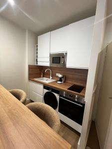 a kitchen with white cabinets and a table with chairs at Appartement hyper centre de Caen, refait à neuf, cosy in Caen