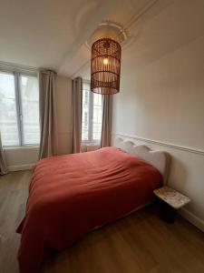 a bedroom with a red bed and a chandelier at Appartement hyper centre de Caen, refait à neuf, cosy in Caen