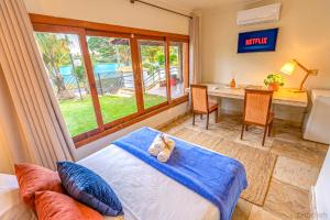 a bedroom with a bed and a desk and a table at Wafeh Pampulha Suítes in Belo Horizonte