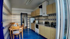 a small kitchen with wooden cabinets and a table and chairs at Casa Inês in Fuzeta