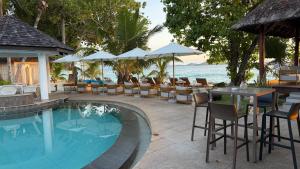 ein Resort mit Swimmingpool, Tischen und Stühlen in der Unterkunft Castello Beach Hotel in Grand'Anse Praslin