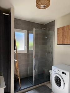 a bathroom with a shower and a washing machine at Mini villa piscine et plage in Cervione