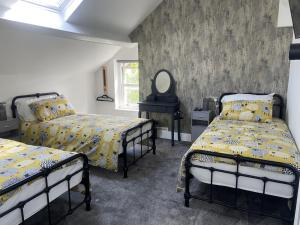 a bedroom with three beds and a mirror at Martris House in Rhayader