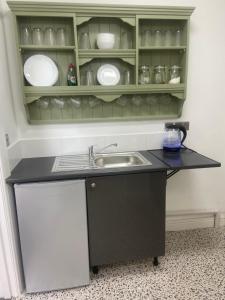 a kitchen with a sink and a shelf with dishes at Martris House in Rhayader