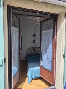 a door to a room with a bed and a ceiling fan at Chez Anna et Mat in Sérignan