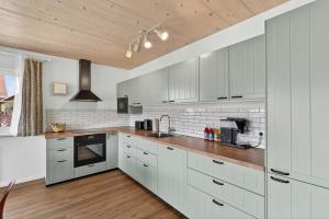 a kitchen with white cabinets and a wooden ceiling at FeWo Nägeleried - Große Galerie-Wohnung mit Balkon, Heimkino, Garten in Sulzberg +57 photos
