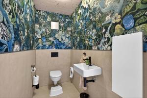 a bathroom with a sink and a toilet and floral wallpaper at FeWo Nägeleried - Große Galerie-Wohnung mit Balkon, Heimkino, Garten in Sulzberg