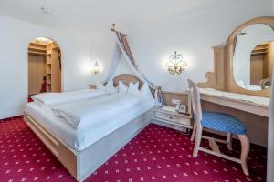 ein Schlafzimmer mit Bett, Schminktisch und Spiegel in der Unterkunft Hotel Serles in Mieders + 46 Fotos