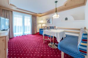 ein Hotelzimmer mit Tisch, Stühlen und Fernseher in der Unterkunft Hotel Serles in Mieders