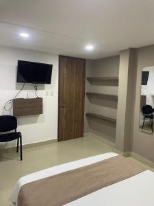 a bedroom with a bed and a flat screen tv at Hotel Santo Rio Suite Santa Marta in Santa Marta