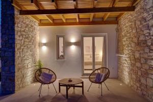 two chairs and a table in a room with a stone wall at Sunshine Alkyoni Suite in Isterni