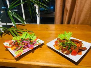 two plates of food on a wooden table at Infinity Winter Resort in Nuwara Eliya