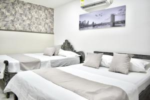 two beds in a room with white walls at Hotel Santo Rio Suite Santa Marta in Santa Marta