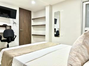 a bedroom with a bed and a chair and a television at Hotel Santo Rio Suite Santa Marta in Santa Marta