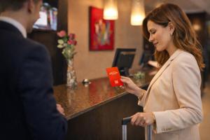 a woman holding a credit card in front of a counter at Hotel CH Bucharest in Bucharest