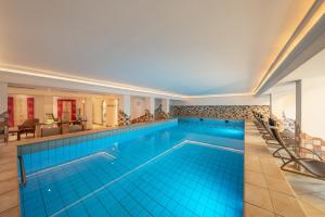ein großes Schwimmbecken mit blauen Fliesen in einem Gebäude in der Unterkunft Hotel Serles in Mieders