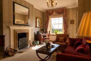 ein Wohnzimmer mit einem roten Sofa und einem Kamin in der Unterkunft Lucknam Park, Emblems Collection in Chippenham