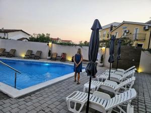 a woman walking by a pool with chairs and umbrellas at Apartman Quattro 2 in Međugorje
