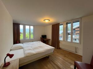 a bedroom with a large bed and two windows at Hotel Sternen Budget in Lenk